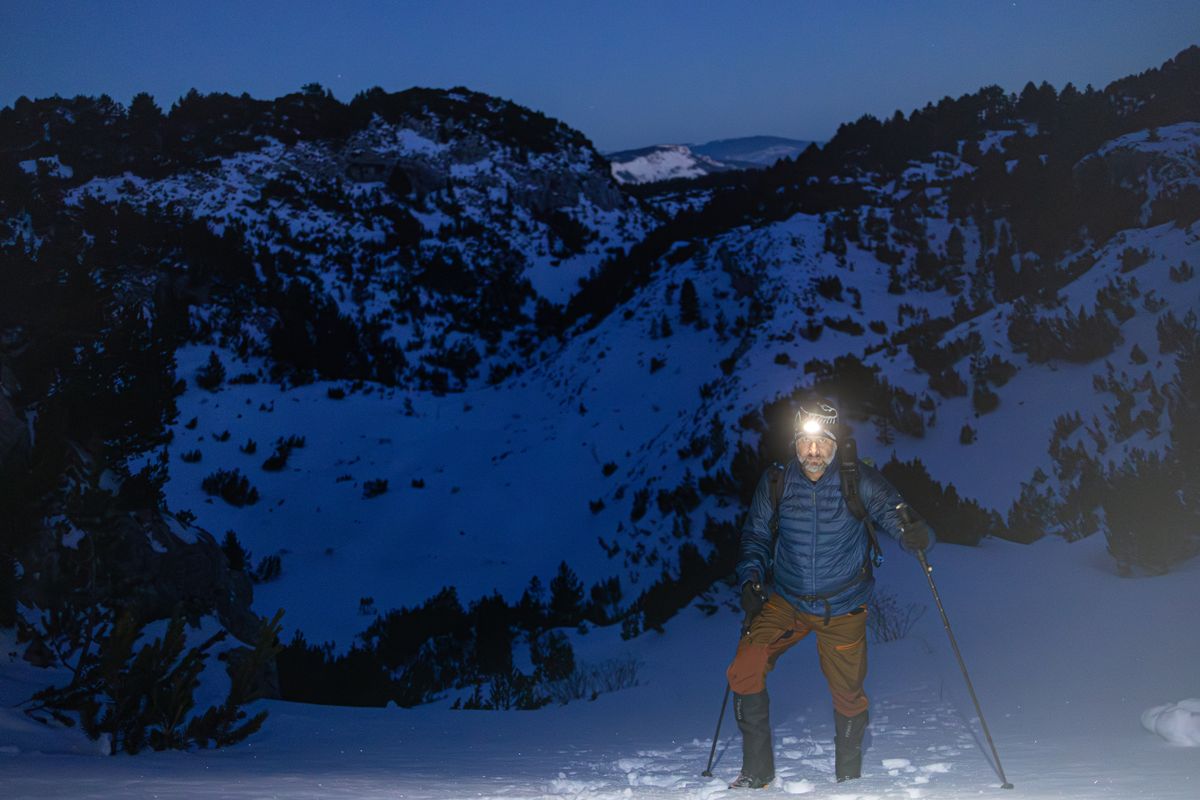 Wanderer mit Stirnlampe im nächtlichen Schnee