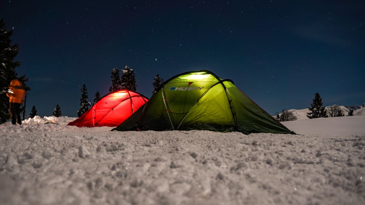 Zwei beleuchtete Zelte im Schnee unter Sternen
